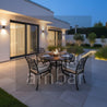 Outdoor patio with a dining table and chairs by a modern house at night.