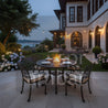 Outdoor patio with fire pit table and chairs in a garden setting at dusk.