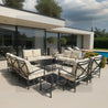 Outdoor patio furniture set with beige cushions on a modern patio with pool and house in the background.
