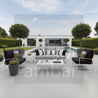 Outdoor patio set with gray sofa, black chairs, and white coffee table in a garden setting.