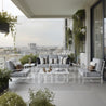 Modern outdoor seating area with gray sofa, chairs, and coffee table on a balcony with cityscape view.