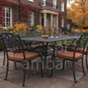 Outdoor patio set with black metal table and chairs with brown cushions in front of a brick building.