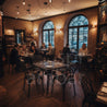 Amalfi Masa Takımı – Klasik restoranlar için mat siyah döküm alüminyum kare masa seti. Dining area with brick walls, large windows, and patrons seated at tables.