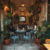 Shark Masa Takımı – Bohem ve Endüstriyel Cafeler İçin Katlanabilir Tasarım Mobilya - People sitting at tables in a cozy restaurant with plants and string lights.