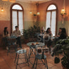 Shark Masa Takımı – Cozy Cafeler İçin Katlanabilir Tasarım Mobilya - People sitting at tables in a cozy cafe with plants and warm lighting.