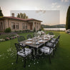 Outdoor dining setup on a lawn with a house and lake in the background